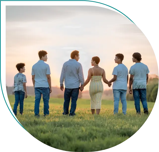 A group of people standing in the grass holding hands.