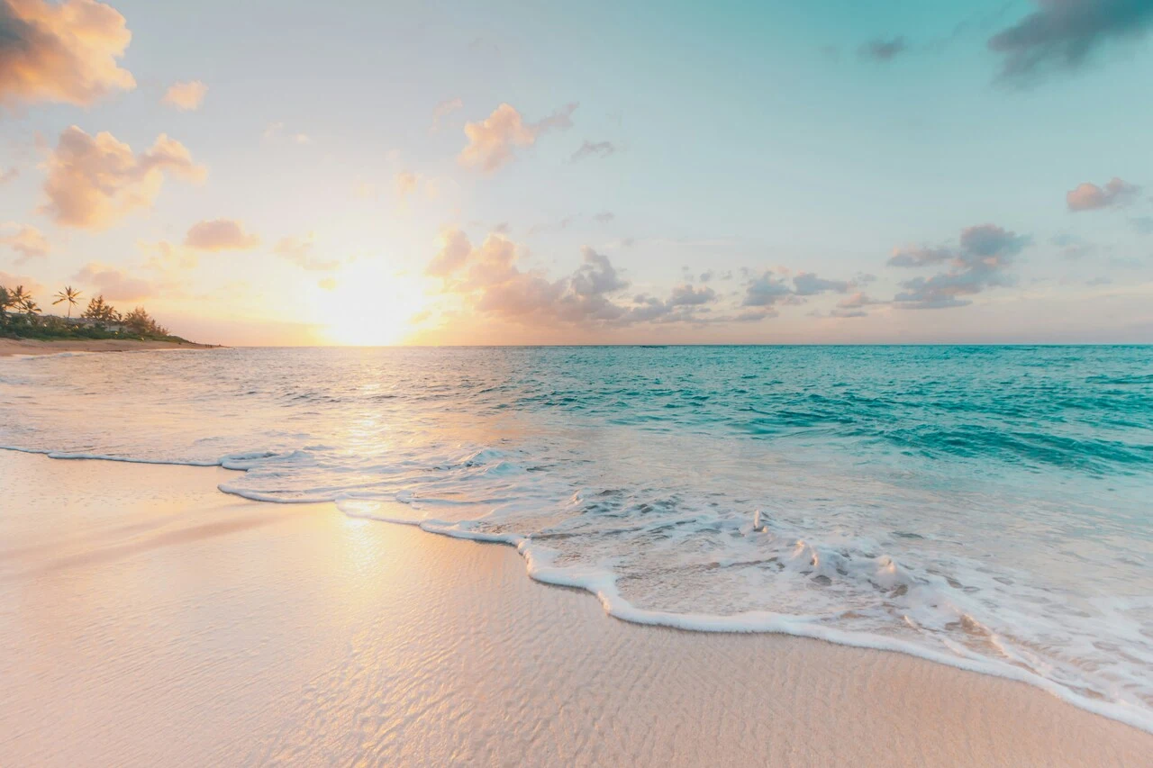 A beach with the sun setting in the background.